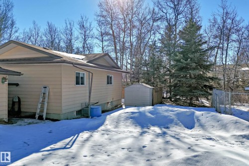 The property features light-colored siding, a dark roof, and several windows visible on its side - 100 23016 Twp Rd 504, Rural Leduc County, AB - Outdoor