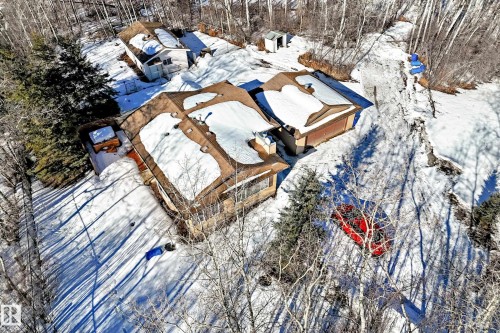 Aerial view of the property showing multiple structures with snow-covered roofs, surrounded by trees - 100 23016 Twp Rd 504, Rural Leduc County, AB - Outdoor