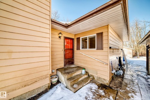 The property features exterior siding, concrete steps, and a screen door - 100 23016 Twp Rd 504, Rural Leduc County, AB - Outdoor With Exterior