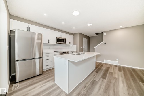 Contemporary kitchen featuring an island with an undermount sink and white countertops - 20415 16 Avenue, Edmonton, AB 