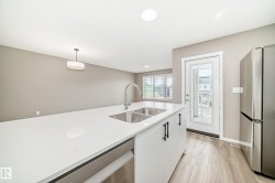 Kitchen island featuring a double basin stainless steel sink, a gooseneck faucet, and white countertops - 