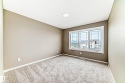 Neutral-toned room featuring a large triple window with white trim, recessed ceiling lighting, and a textured gray carpet - 