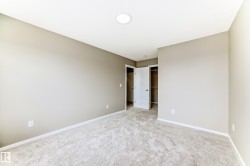 Neutral-toned room featuring light-colored carpeting, white baseboards, and a recessed ceiling light fixture - 