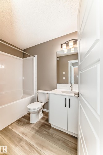 Full bathroom featuring a white vanity with a white countertop and sink, black cabinet pulls, a toilet, and a tub/shower combination with a white subway tile surround - 20415 16 Avenue, Edmonton, AB 