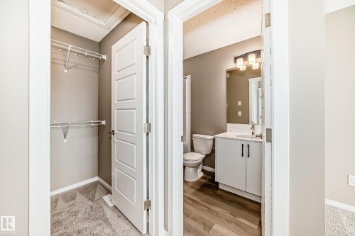 Modern bathroom featuring a white vanity with dark hardware, a rectangular mirror, and wood-finish flooring - 20415 16 Avenue, Edmonton, AB 