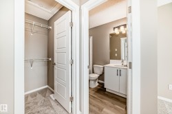 Modern bathroom featuring a white vanity with dark hardware, a rectangular mirror, and wood-finish flooring - 