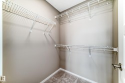 Walk-in closet featuring neutral-toned walls, white wire shelving, white trim, and textured carpet flooring - 