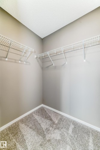 Closet space featuring wire shelving systems, neutral-toned walls, and patterned carpeting - 20415 16 Avenue, Edmonton, AB 
