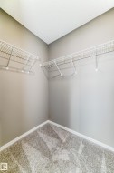 Closet space featuring wire shelving systems, neutral-toned walls, and patterned carpeting - 