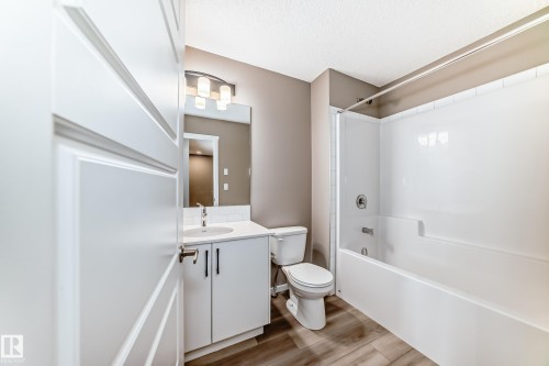 Bathroom featuring a white vanity with an undermount sink, a white subway tile backsplash, a chrome faucet, and a large mirror - 20415 16 Avenue, Edmonton, AB 