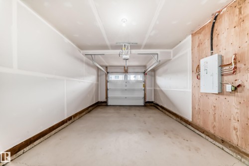 Single-car garage with a concrete floor, white drywall walls, and an overhead garage door opener - 20415 16 Avenue, Edmonton, AB 