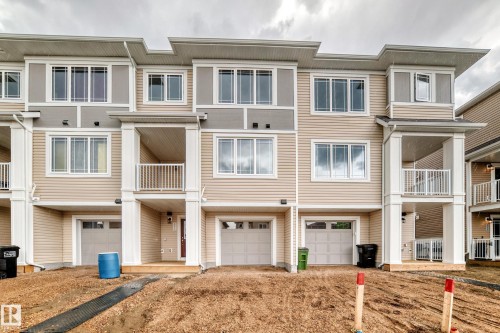 Multi-level townhome exterior featuring light beige siding and gray accents - 20415 16 Avenue, Edmonton, AB 