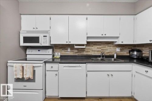 Kitchen featuring white cabinetry, a tile backsplash, and a double basin stainless steel sink - 3240 130A Avenue, Edmonton, AB - Indoor Photo Showing Kitchen With Double Sink