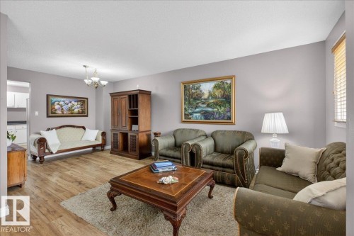 Living area featuring wood-look flooring, a chandelier light fixture, and blinds on the window - 3240 130A Avenue, Edmonton, AB - Indoor Photo Showing Living Room