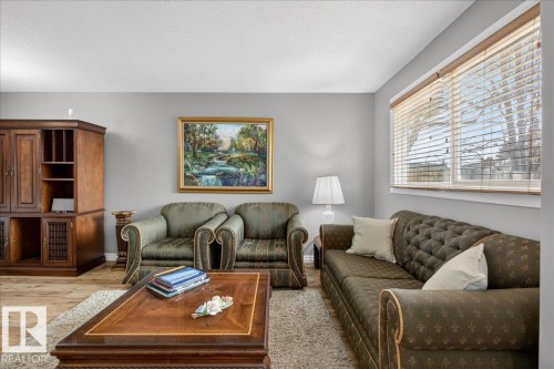 This living area features a window with horizontal blinds, light gray walls, and light-colored flooring - 3240 130A Avenue, Edmonton, AB - Indoor Photo Showing Living Room