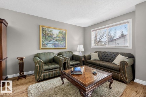 Living room featuring a large window with blinds, light gray walls, and wood flooring - 3240 130A Avenue, Edmonton, AB - Indoor Photo Showing Living Room