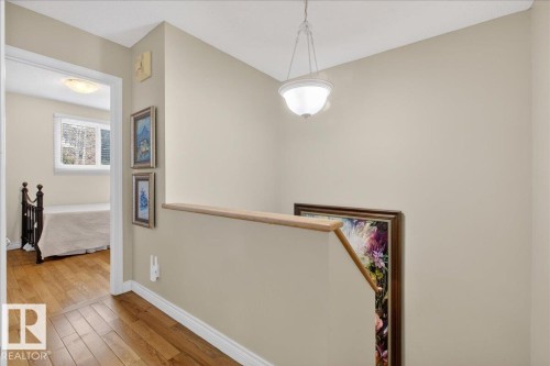 The property features a staircase with a wooden handrail, leading to a hallway with hardwood floors - 3240 130A Avenue, Edmonton, AB - Indoor Photo Showing Other Room