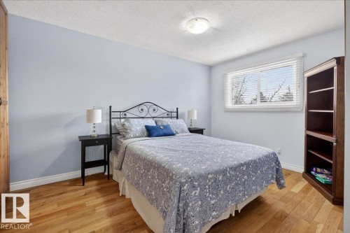This room features light blue walls, hardwood flooring, and a large window with white blinds - 3240 130A Avenue, Edmonton, AB - Indoor Photo Showing Bedroom