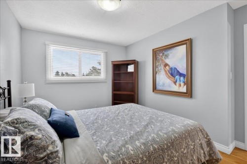 This room features light blue walls, a window with blinds, and hardwood flooring - 3240 130A Avenue, Edmonton, AB - Indoor Photo Showing Bedroom