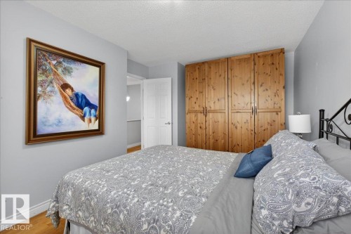Bedroom with light wood flooring and a wall of built-in wood wardrobes - 3240 130A Avenue, Edmonton, AB - Indoor Photo Showing Bedroom