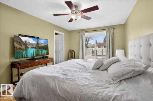 The property features a bedroom with a ceiling fan, a window, and wood flooring - 3240 130A Avenue, Edmonton, AB - Indoor Photo Showing Bedroom