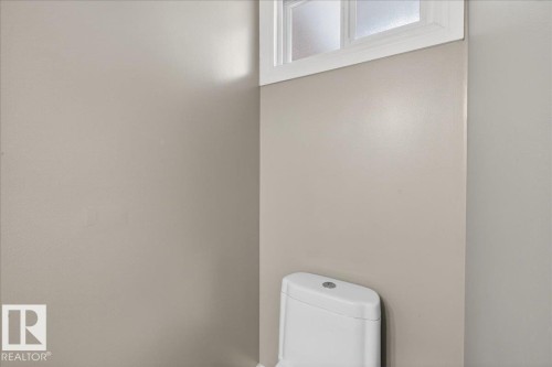 The bathroom features a white toilet and a window with white trim - 3240 130A Avenue, Edmonton, AB - Indoor Photo Showing Other Room