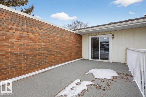 This property features a patio area with a brick wall, a sliding glass door, and white railing - 3240 130A Avenue, Edmonton, AB - Outdoor With Exterior