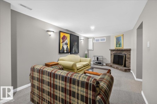 Living area featuring a brick fireplace, grey carpeting, and light grey walls - 3240 130A Avenue, Edmonton, AB - Indoor With Fireplace