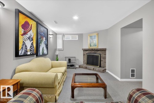 Living room featuring a brick fireplace with a black fire screen, light grey walls, and grey carpet - 3240 130A Avenue, Edmonton, AB - Indoor