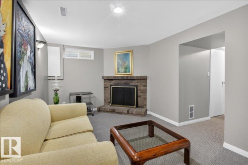 The living area features a brick fireplace, grey carpeting, and light grey walls - 3240 130A Avenue, Edmonton, AB - Indoor