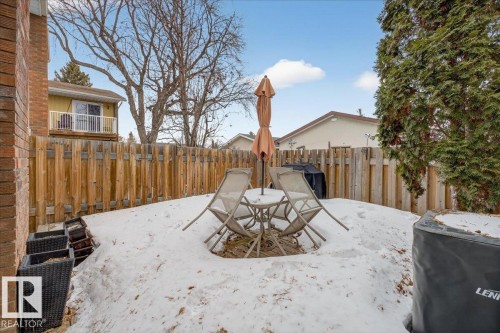 The property features a fenced yard with a patio area, complete with an outdoor table and chairs, and a freestanding umbrella - 3240 130A Avenue, Edmonton, AB - Outdoor