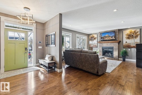 Inviting entryway with a vibrant green door and an overhead geometric light fixture - 11409 63 Street Nw, Edmonton, AB - Indoor Photo Showing Living Room With Fireplace