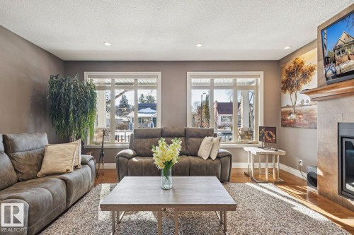 Living room featuring recessed lighting, hardwood flooring, and large windows that provide natural light - 11409 63 Street Nw, Edmonton, AB - Indoor Photo Showing Living Room With Fireplace