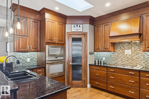 Kitchen featuring wood cabinetry, stainless steel appliances, a black countertop, and a tiled backsplash - 11409 63 Street Nw, Edmonton, AB - Indoor Photo Showing Kitchen With Double Sink With Upgraded Kitchen