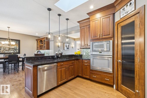 The kitchen features wood cabinetry, dark countertops, and stainless steel appliances including a dishwasher, microwave, and oven - 11409 63 Street Nw, Edmonton, AB - Indoor Photo Showing Kitchen