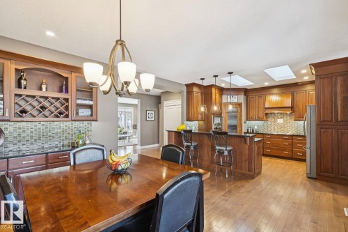 Open-concept kitchen and dining area featuring hardwood flooring, extensive wood cabinetry, and a kitchen island with seating - 11409 63 Street Nw, Edmonton, AB - Indoor Photo Showing Dining Room