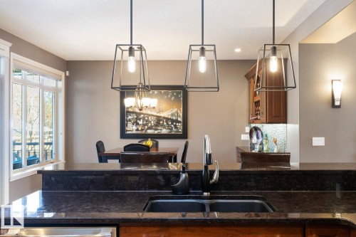 Kitchen featuring a dark granite countertop with an undermount sink and a modern faucet - 11409 63 Street Nw, Edmonton, AB - Indoor Photo Showing Kitchen