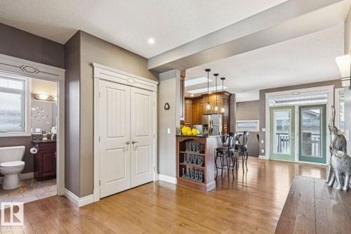 Open concept living space featuring hardwood floors, a kitchen island with pendant lighting, and double glass doors leading to an outdoor area - 11409 63 Street Nw, Edmonton, AB - Indoor