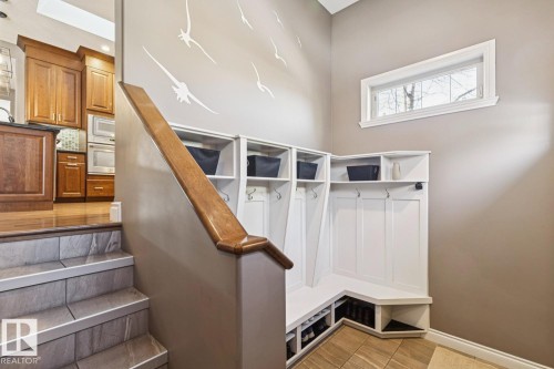Entryway featuring a built-in white storage bench with hooks and cubbies, a window, and tiled flooring - 11409 63 Street Nw, Edmonton, AB - Indoor Photo Showing Other Room