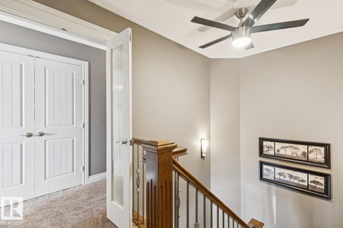This area features a contemporary ceiling fan with integrated lighting, a wooden staircase with metal balusters, and elegant wall sconces providing ambient light - 11409 63 Street Nw, Edmonton, AB - Indoor Photo Showing Other Room