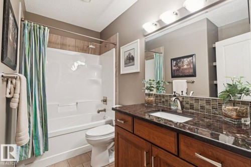 Bathroom featuring a combination bathtub and shower, a single vanity with a granite countertop, and a large mirror with overhead lighting - 11409 63 Street Nw, Edmonton, AB - Indoor Photo Showing Bathroom