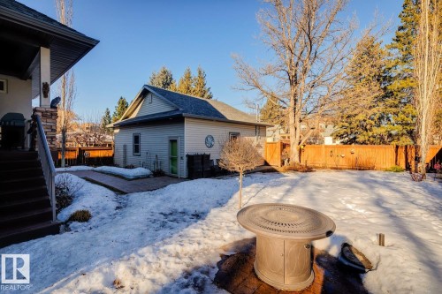 The property features an extensive yard with a fire pit area, a detached structure, and a wooden fence - 11409 63 Street Nw, Edmonton, AB - Outdoor