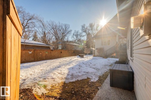 The property features a fenced yard with a partially snow-covered lawn, a concrete pathway, and an exterior with horizontal siding - 11409 63 Street Nw, Edmonton, AB - Outdoor