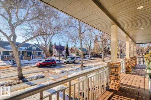 The property features an elevated porch with stone-clad columns, a wood-look deck surface, and white railings - 11409 63 Street Nw, Edmonton, AB - Outdoor With Deck Patio Veranda