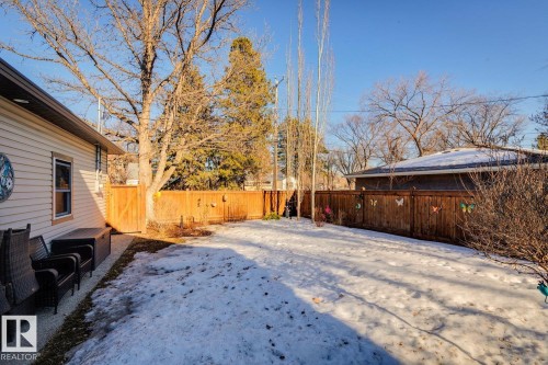 The property features a fenced yard with a gate, a paved patio area, and mature trees - 11409 63 Street Nw, Edmonton, AB - Outdoor