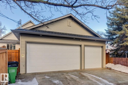 The property features a garage with two white garage doors, exterior siding, and a fenced perimeter - 11409 63 Street Nw, Edmonton, AB - Outdoor
