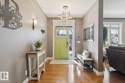 Inviting entryway featuring hardwood floors, a light green door with glass panes, and a modern ceiling light fixture - 11409 63 Street Nw, Edmonton, AB - Indoor Photo Showing Other Room