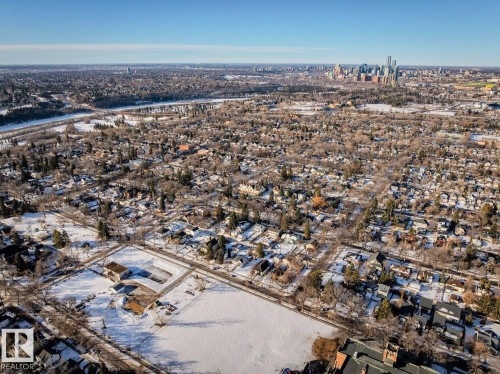 Aerial view of the neighbourhood, featuring residential properties, trees, a river, and a distant city skyline - 11409 63 Street Nw, Edmonton, AB - Outdoor With View