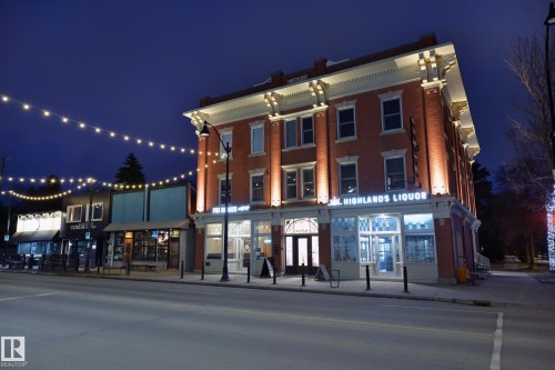 The property features a multi-story brick facade with decorative white trim and illuminated signage - 11409 63 Street Nw, Edmonton, AB - Outdoor