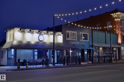 The property features a storefront with a prominent sign and a clock, illuminated by overhead lighting - 11409 63 Street Nw, Edmonton, AB - Outdoor